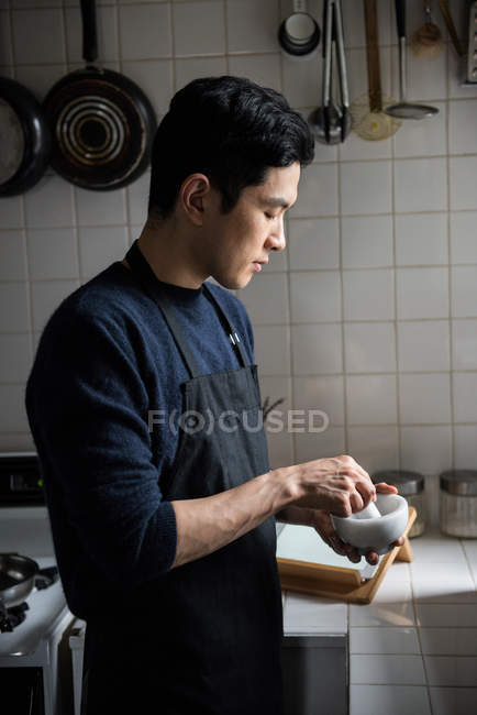 Man using pestle and mortar in kitchen at home — Stock Photo