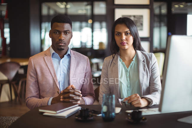 Портрет бизнесмена и коллеги за столом в офисе — стоковое фото
