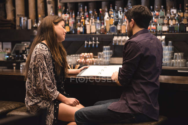 Casal discutindo sobre menu no balcão de bar — Fotografia de Stock