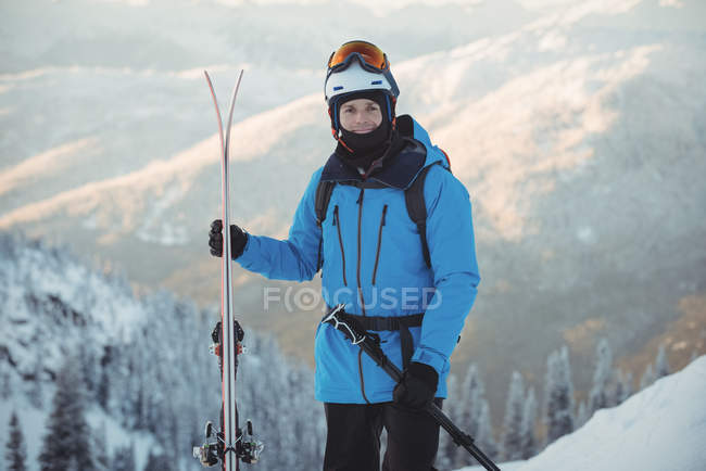 Porträt eines Skifahrers, der mit Ski in verschneiter Landschaft steht — Stockfoto