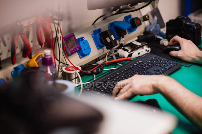 Nahaufnahme eines Mannes, der in einem Elektronikreparaturzentrum am Desktop-PC arbeitet — Stockfoto
