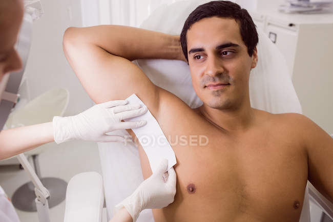 Médico depilando la piel del paciente masculino en la clínica - foto de stock