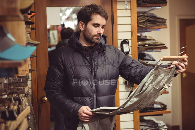 Hombre seleccionando ropa en una tienda de ropa - foto de stock