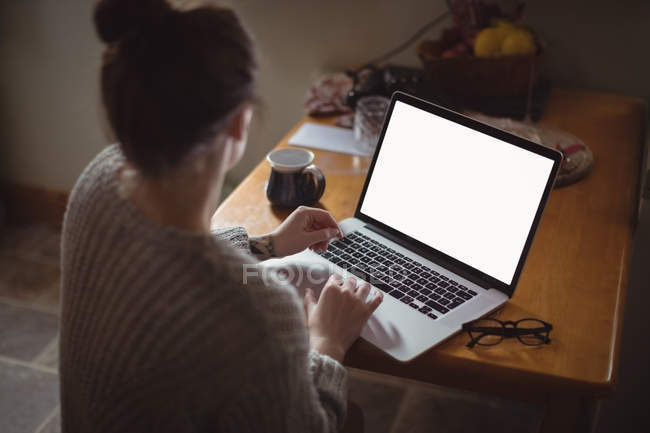 Жінка використовує ноутбук на столі на кухні вдома — стокове фото
