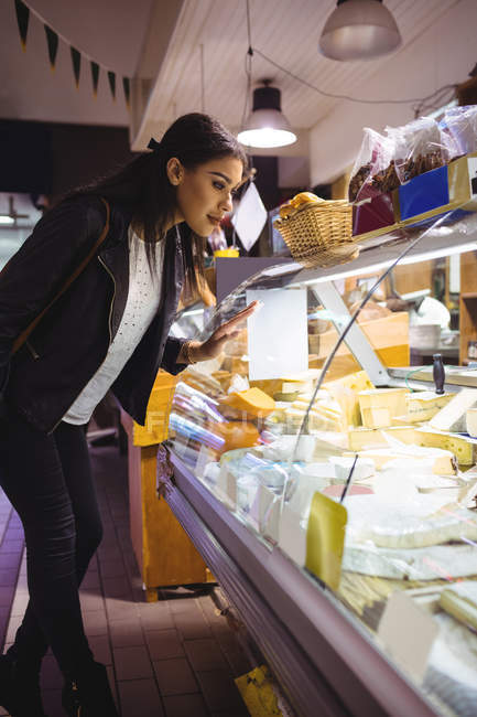 Mulher olhando para exibição de queijo no supermercado — Fotografia de Stock