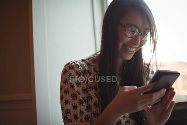 Woman using mobile phone near window at cafe — Stock Photo