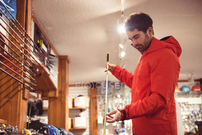 Красивый человек выбирает лыжную палку в магазине — стоковое фото