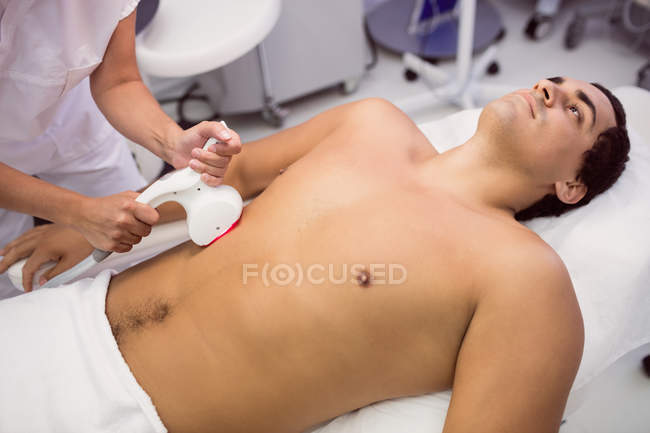 Hombre recibiendo tratamiento de depilación láser en la clínica - foto de stock