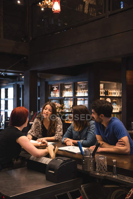Бармен, взаимодействующий с клиентами за барной стойкой — стоковое фото