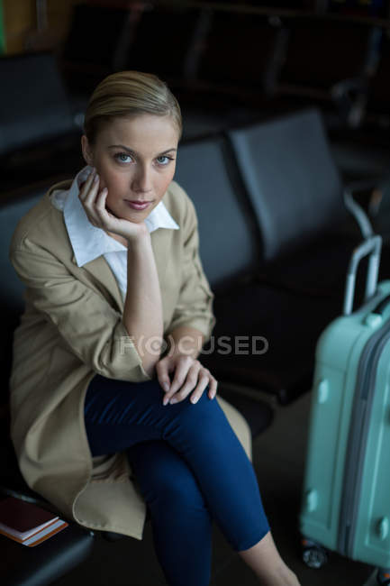 Retrato de la mujer sentada en la silla en la sala de espera en la terminal del aeropuerto - foto de stock