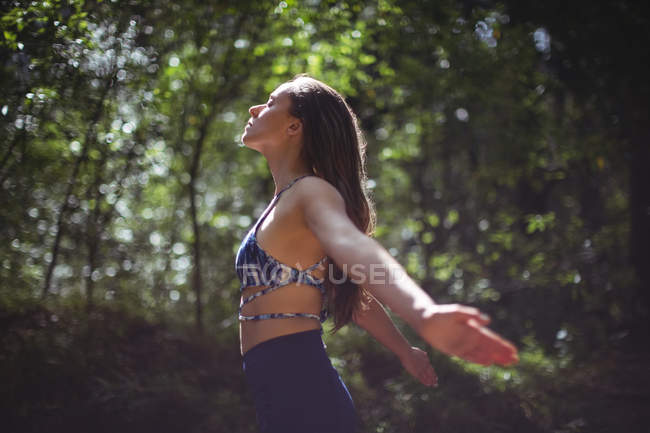 Женщина выполняет упражнения на растяжку в лесу — стоковое фото