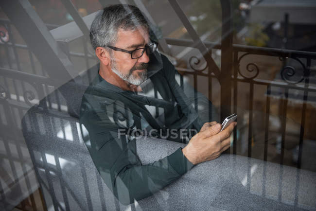 Homem usando telefone celular na sala de estar em casa — Fotografia de Stock