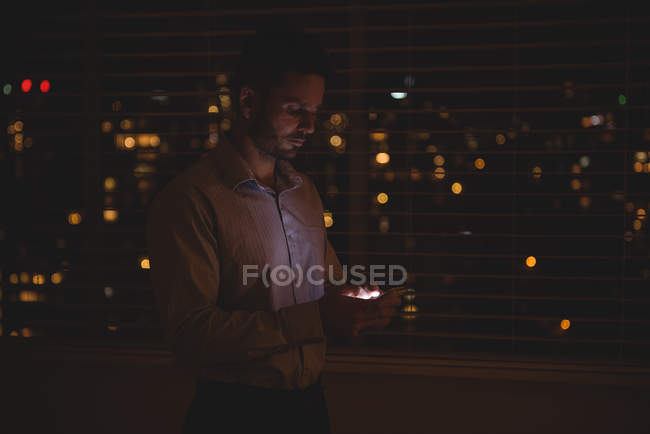 Man using his mobile phone near window blinds at night — Stock Photo