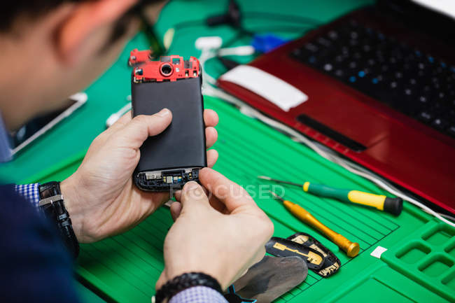Чоловік ремонтує мобільний телефон у ремонтному центрі — стокове фото
