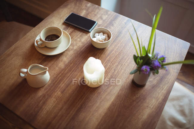 Mobile phone and coffee cup on wooden table in cafe — Stock Photo
