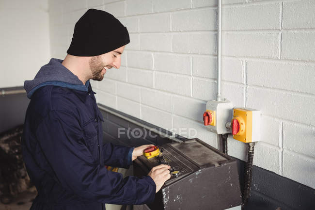 Mecánico usando caja de control en garaje de reparación - foto de stock