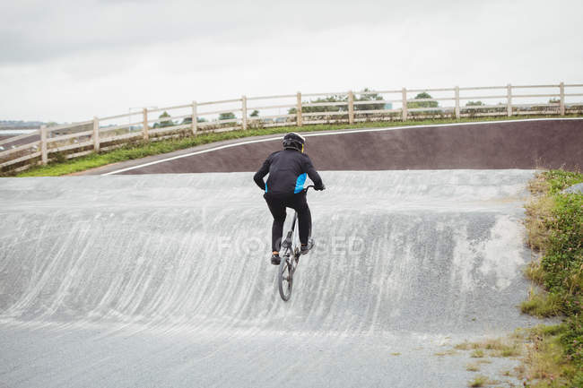 Vista trasera del ciclista montando en bicicleta BMX en skatepark - foto de stock