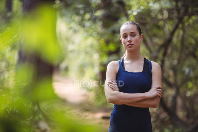 Ritratto di bella donna in piedi con le braccia incrociate nella foresta — Foto stock