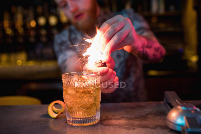 Bartender preparing flaming cocktail at counter in bar — Stock Photo