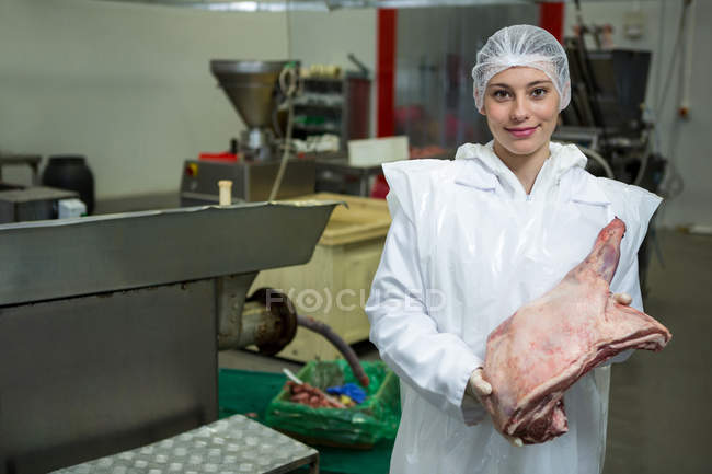 Portrait of female butcher holding meat at meat factory — Stock Photo