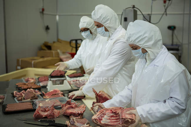 Açougueiros limpando carne crua na fábrica de carne — Fotografia de Stock
