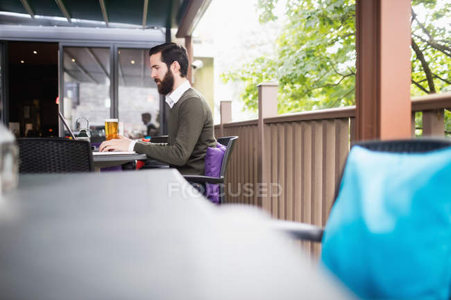 Человек с ноутбуком на террасе бара — стоковое фото