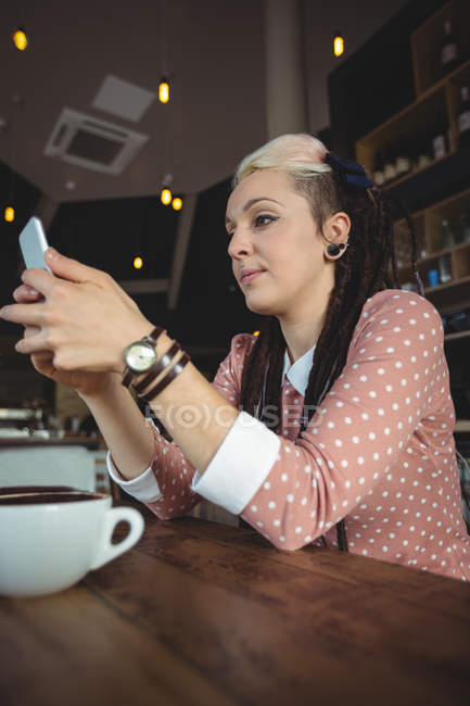 Mujer usando el teléfono móvil en la cafetería - foto de stock