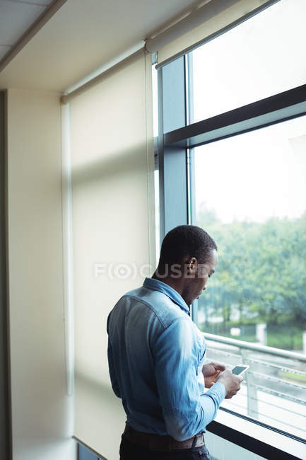 Male business executive using mobile phone in office — Stock Photo