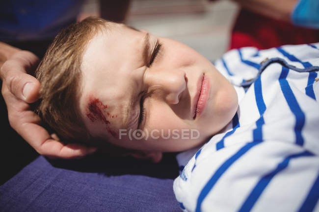 Paramedics examining injured boy on street — Stock Photo