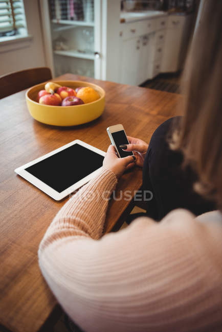 Donna che utilizza il telefono cellulare e tablet digitale a casa — Foto stock