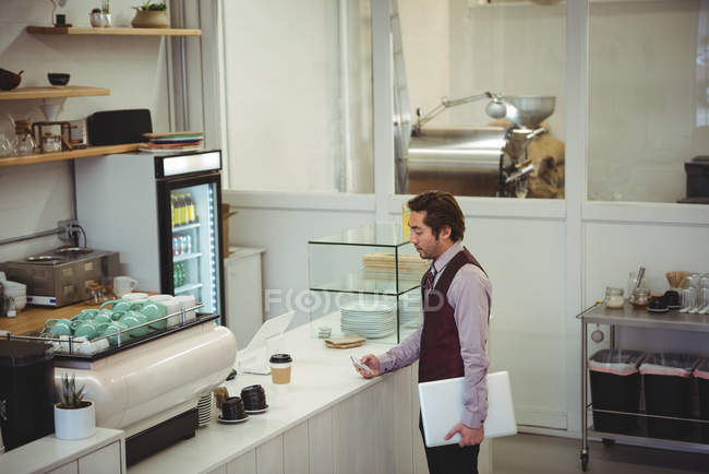 Uomo che utilizza il telefono cellulare in caffetteria — Foto stock