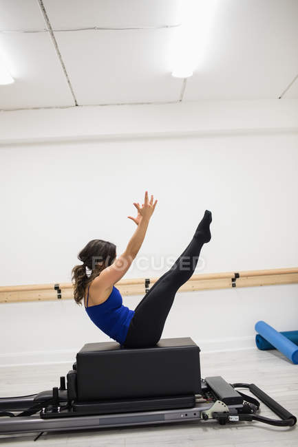 Femme faisant de l'exercice sur l'équipement de réformateur dans la salle de gym — Photo de stock