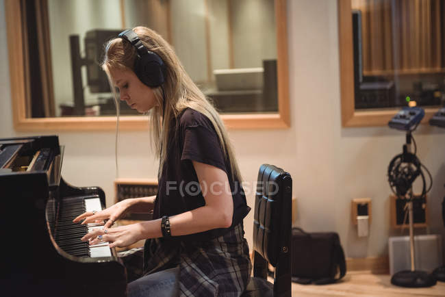 Donna che suona un pianoforte in studio di musica — Foto stock