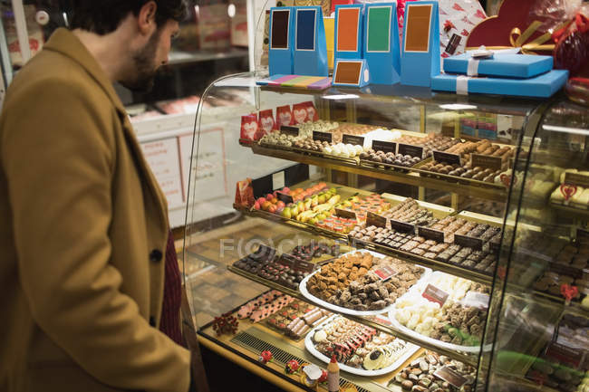 Чоловік дивиться на десерти на десертній стійці в супермаркеті — стокове фото