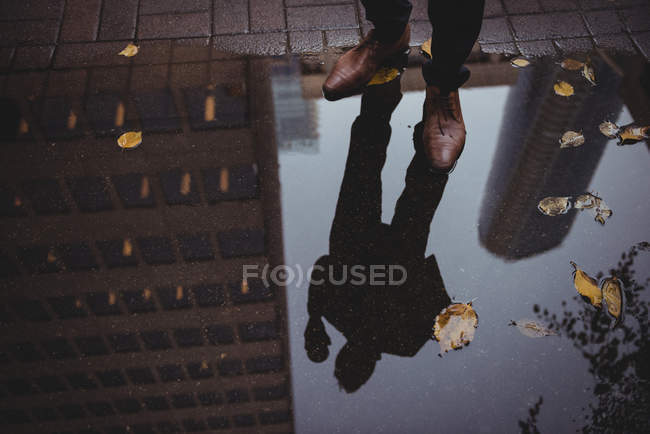 Reflection of a businessman in puddle water on street — Stock Photo