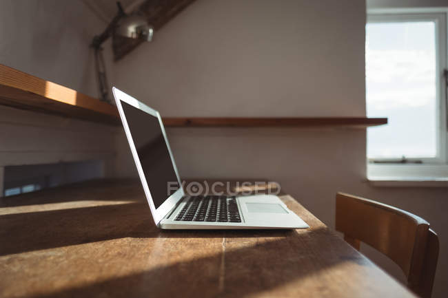 Sonnenlicht fällt auf einen offenen Laptop auf dem Tisch — Stockfoto