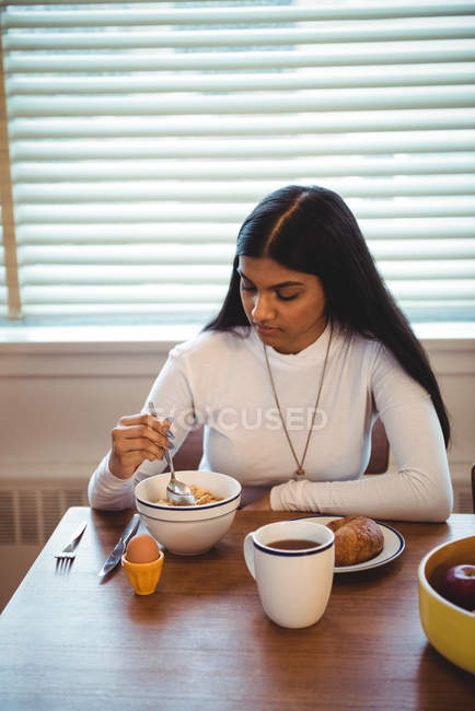 Woman having breakfast in living room at home — Stock Photo