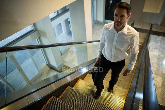 Hombre guapo en escaleras mecánicas en el aeropuerto - foto de stock