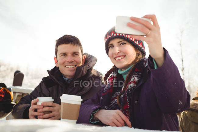Feliz casal esquiador clicando em uma selfie na estância de esqui — Fotografia de Stock