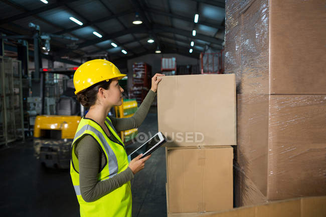 Female worker using digital tablet while working in warehouse — Stock Photo