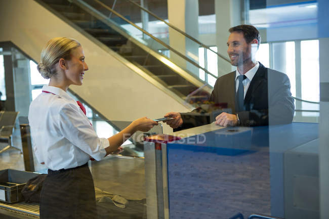 Женщины-сотрудники выдают посадочный талон бизнесмену за стойкой регистрации — стоковое фото