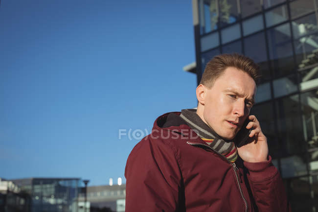 Executivo masculino falando no celular na rua em frente ao prédio de escritórios — Fotografia de Stock