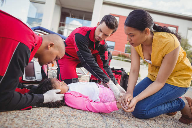 Парамедики вивчають поранену дівчину на вулиці — стокове фото