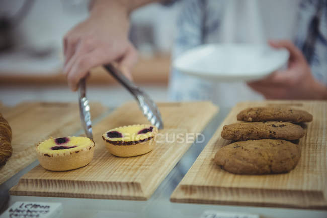 Hand picking a cookie from tong in coffee shop — Stock Photo
