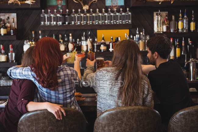 Vue arrière d'amis qui trinquent avec de la bière et des verres à cocktail au bar — Photo de stock