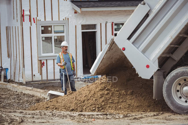 Travailleur de la construction debout près de la benne sur le chantier — Photo de stock
