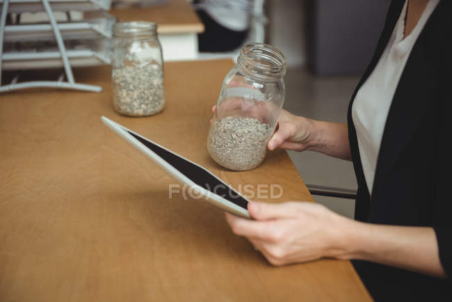 Mid section of business executive looking at jar of pebbles in office — Stock Photo