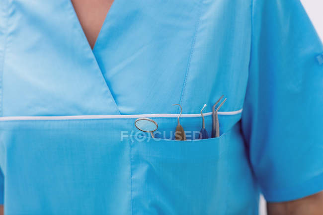 Section médiane du dentiste portant des outils dentaires dans une poche dans une clinique dentaire — Photo de stock