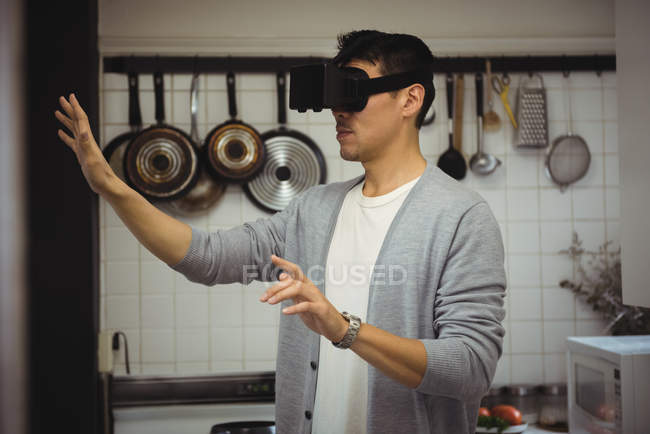 Homem experimentando fone de ouvido realidade virtual na cozinha em casa — Fotografia de Stock