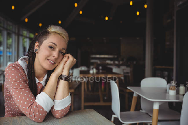 Retrato de una mujer sonriente sentada en la cafetería - foto de stock